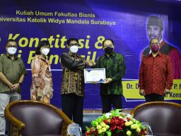 Hakim MK Daniel Yusmic P. Foekh menerima sertifikat penghargaan dari Rektor UKWMS Kuncoro Foe.(Foto: Humas UKWMS)