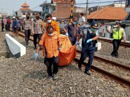Petugas mengevakuasi tubuh korban yang tertabrak kereta api di Tandes. (Foto: info kedaruratan 112)