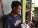 Risky Junianto menggendong putranya yang mengalami kelainan tidak memiliki anus