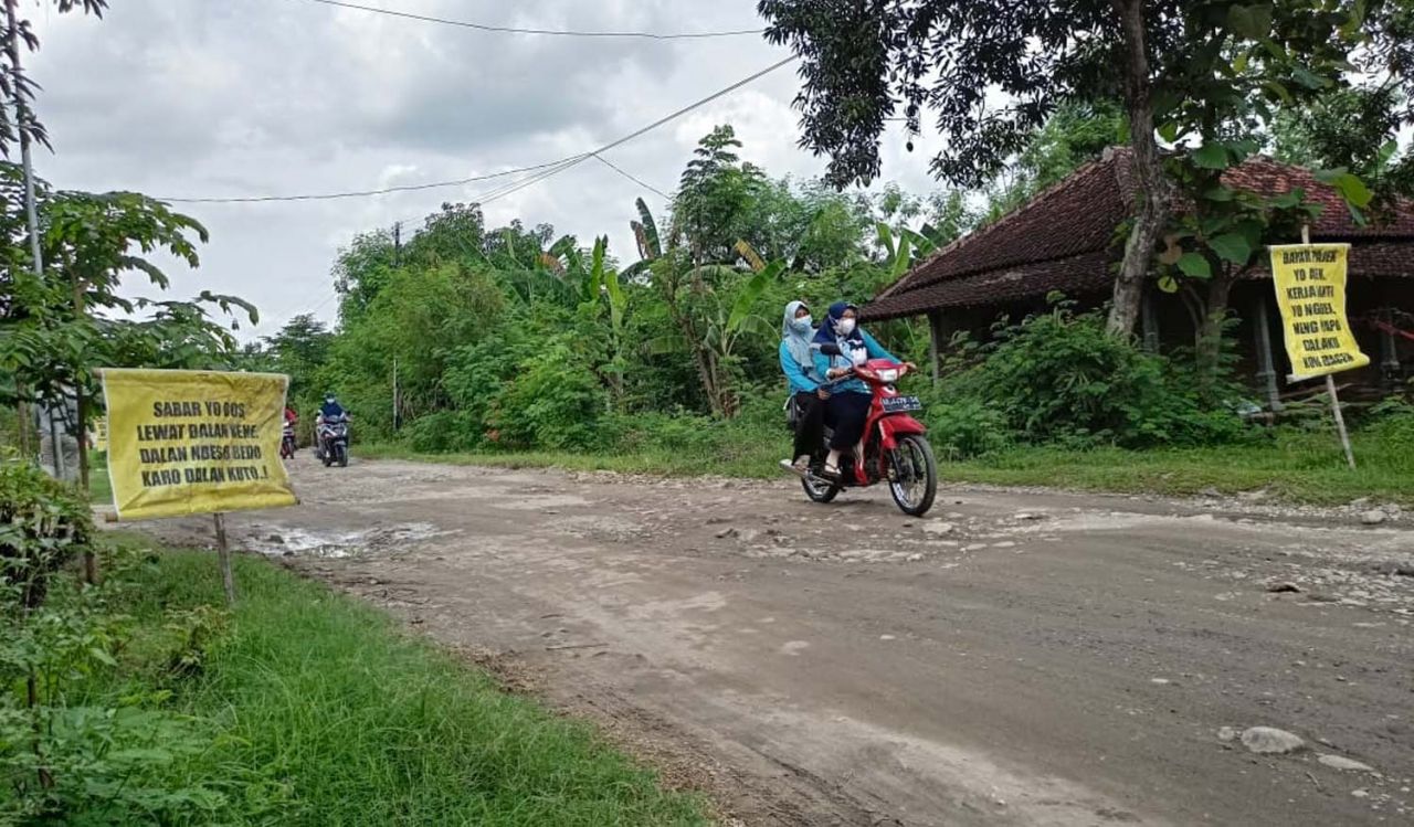 Salah satu banner berisi tulisan satire yang terpasang di jalan rusak di Ponorogo