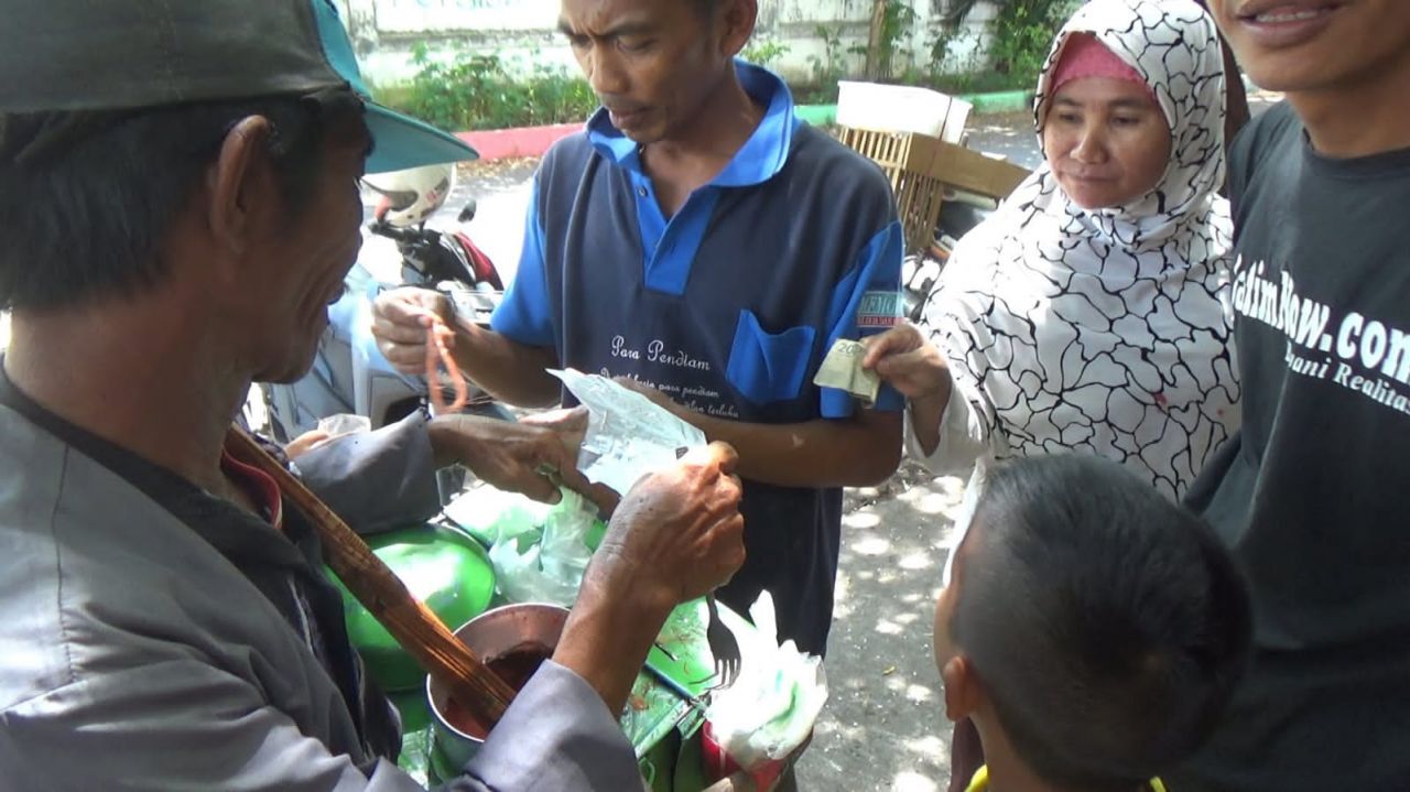 Kakek Tohir melayani pembeli jajanan rambut nenek.