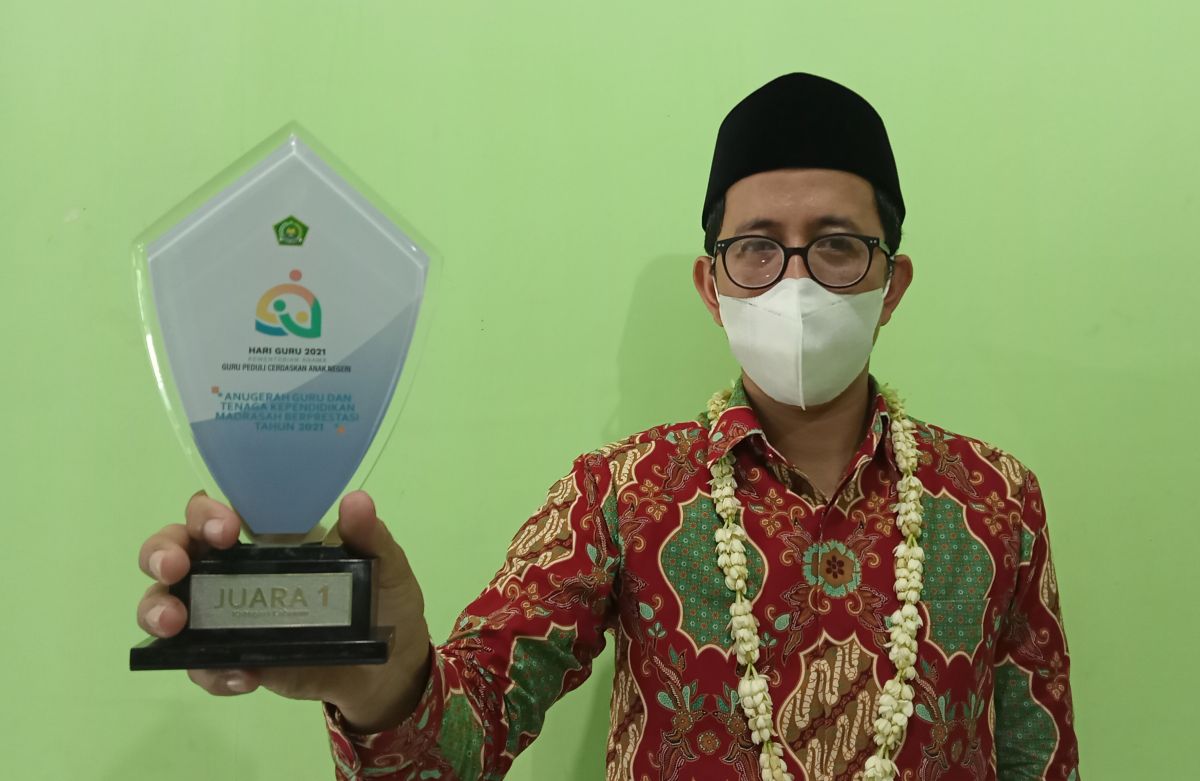 Guru MTs NU Terate Gresik, Muhammad Faiq Rofiqi menunjukkan piala juara 1 atas alat peraga Biobaterai yang diciptakannya