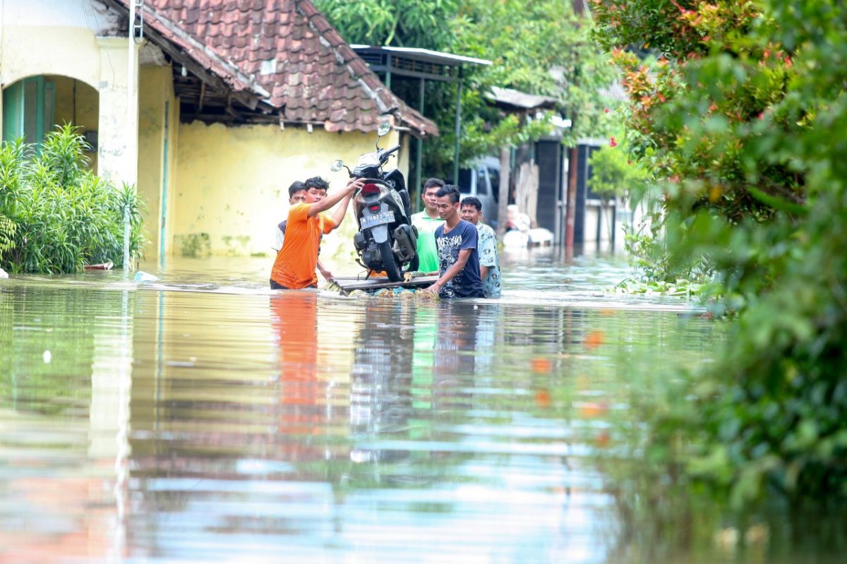 Warga mengevakuasi kendaraan bermotor untuk melintasi banjir di Kecamatan Rejoso.