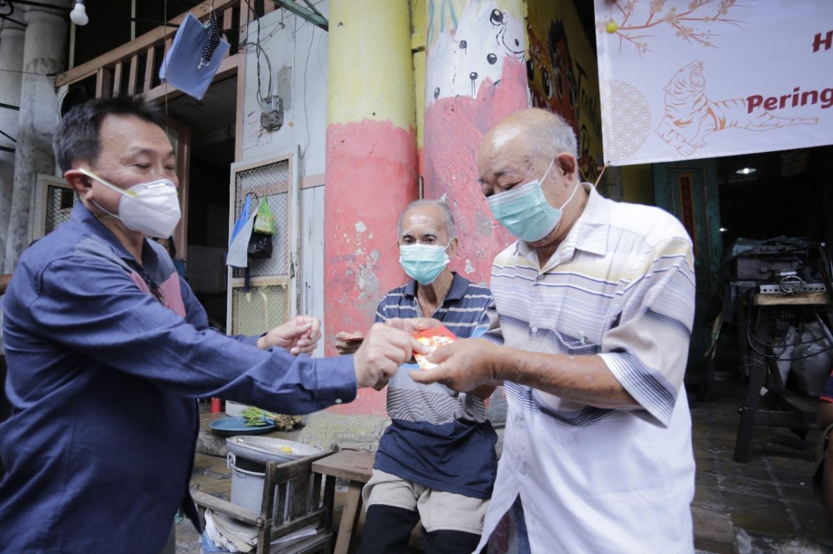 Salah satu donatur memberikan bantuan ke salah satu warga Kampung Pecinan, Tambak Bayan, Surabaya