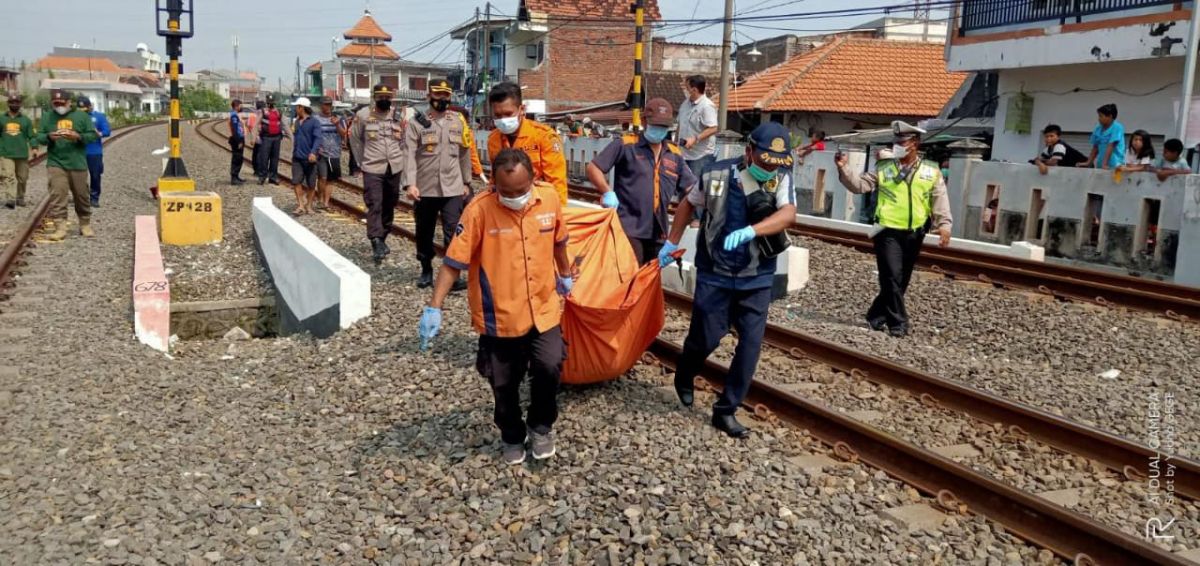 Petugas mengevakuasi tubuh korban yang tertabrak kereta api di Tandes. (Foto: info kedaruratan 112)