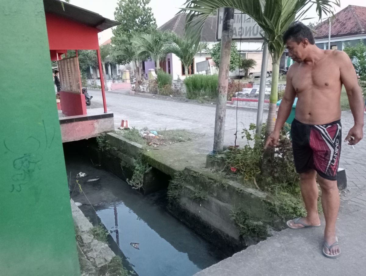 Warga Dusun Jabon, Desa Plosogeneng, saat menunjukkan air saluran pertanian yang timbulkan bau busuk seperti bangkai.(Foto: Elok Aprianto)
