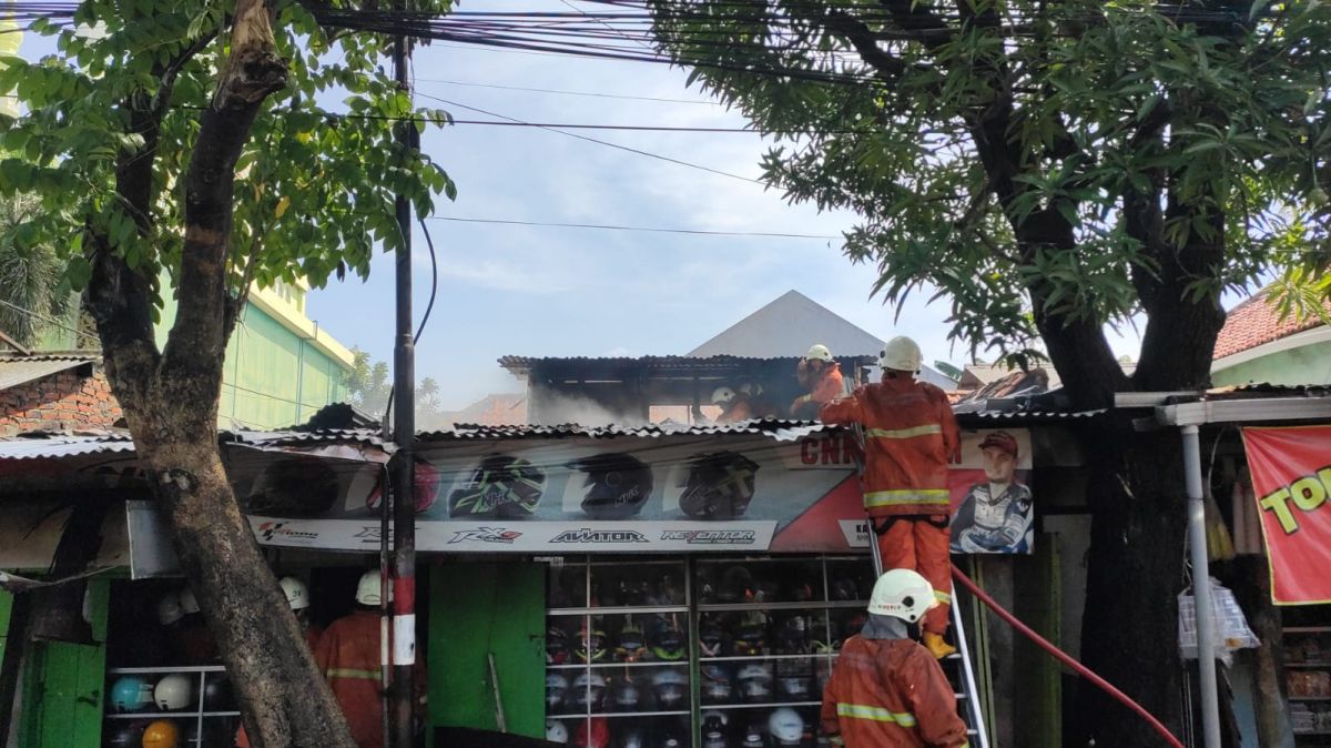 Petugas pemadam kebakaran saat berusaha memadamkan api yang membakar toko helm.(Foto: Info Kedaruratan Surabaya/jatimnow.com)