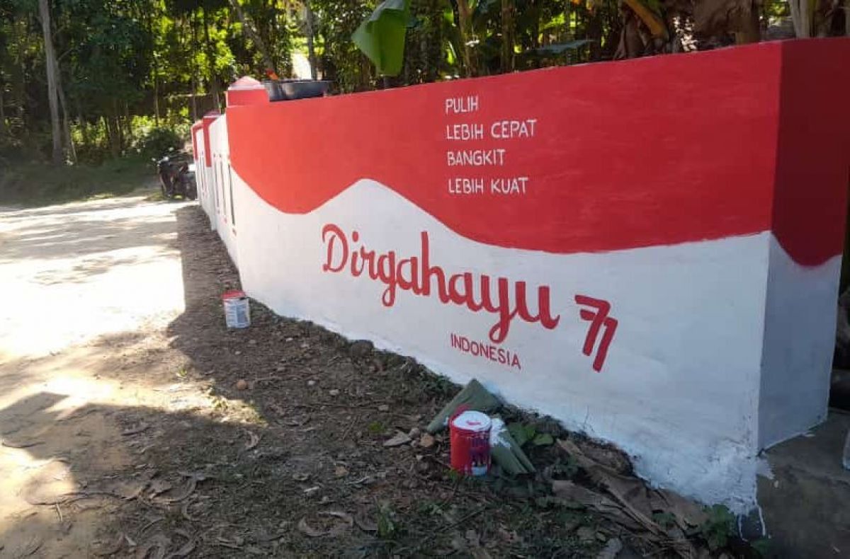 Warga Desa Pekamban Daya mengecat tembok desa jelang hari kemerdekaan RI.