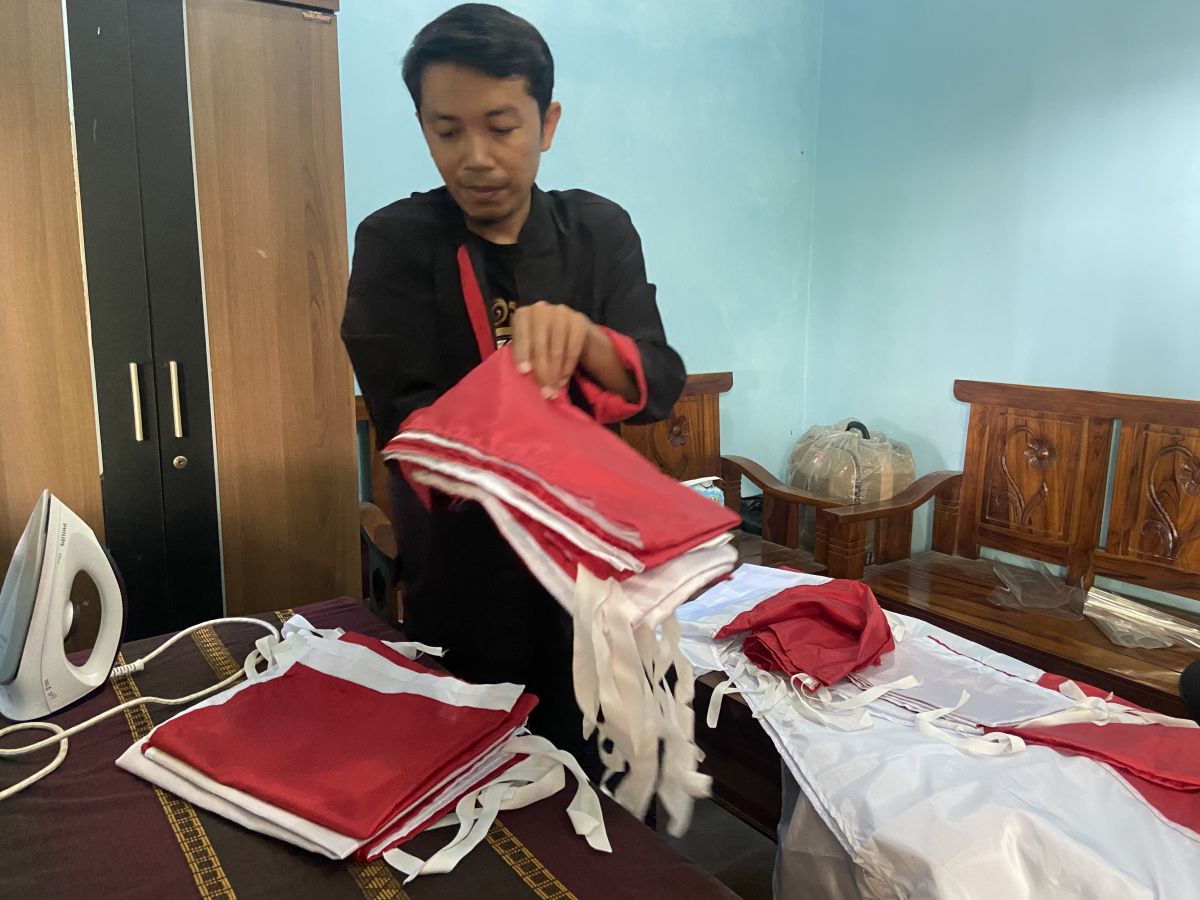 Tarmin membuat sendiri bendera merah putih untuk dibagikan pada warga.