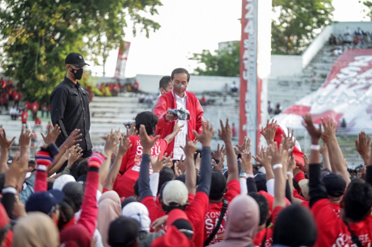 Presiden Jokowi membagikan kaos pada relawan Sapu Lidi Jatim di Surabaya.