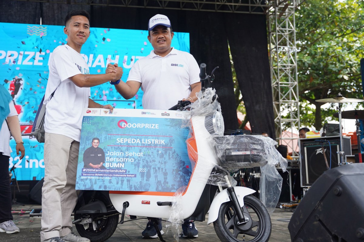 General Manager of CSR SIG Edy Saraya (kanan) menyerahkan sepeda listrik kepada Muhamad Nur Azis, pemenang doorprize utama pada acara Jalan Sehat Bersama BUMN di Kampoeng Rawa, Ambarawa, Semarang