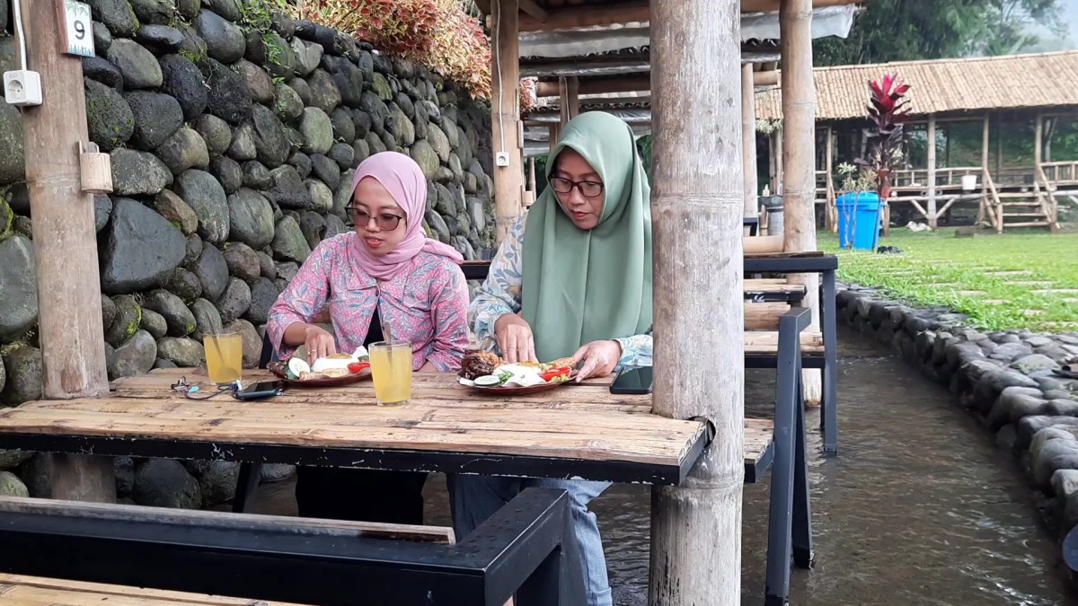 Pengunjung saat menyantap makanan di atas aliran air. (Achmad Supriyadi/jatimnow.com)