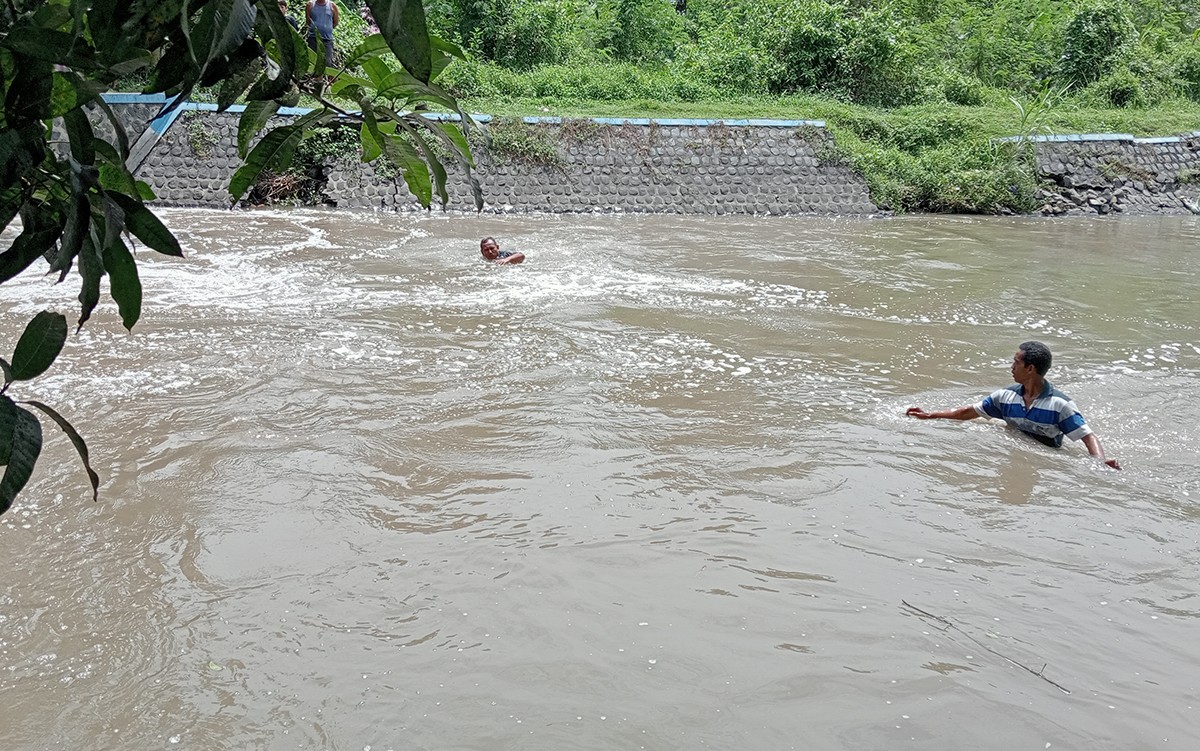 Warga terjun ke aliran sungai untuk mencari korban yang diduga terpeleset saat bermain di tepi sungai. (foto: Elok Aprianto/jatimnow.com)