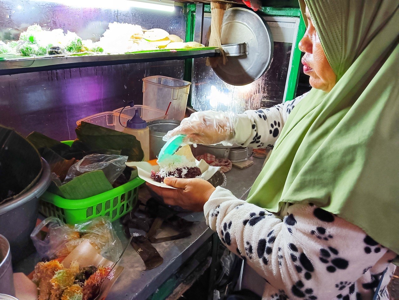 Siti Zaenab, saat meracik pesanan pembeli di Lapak Ketan Maknyus di Pandaan Pasuruan. (Foto: Ahaddiini HM/jatimnow.com).