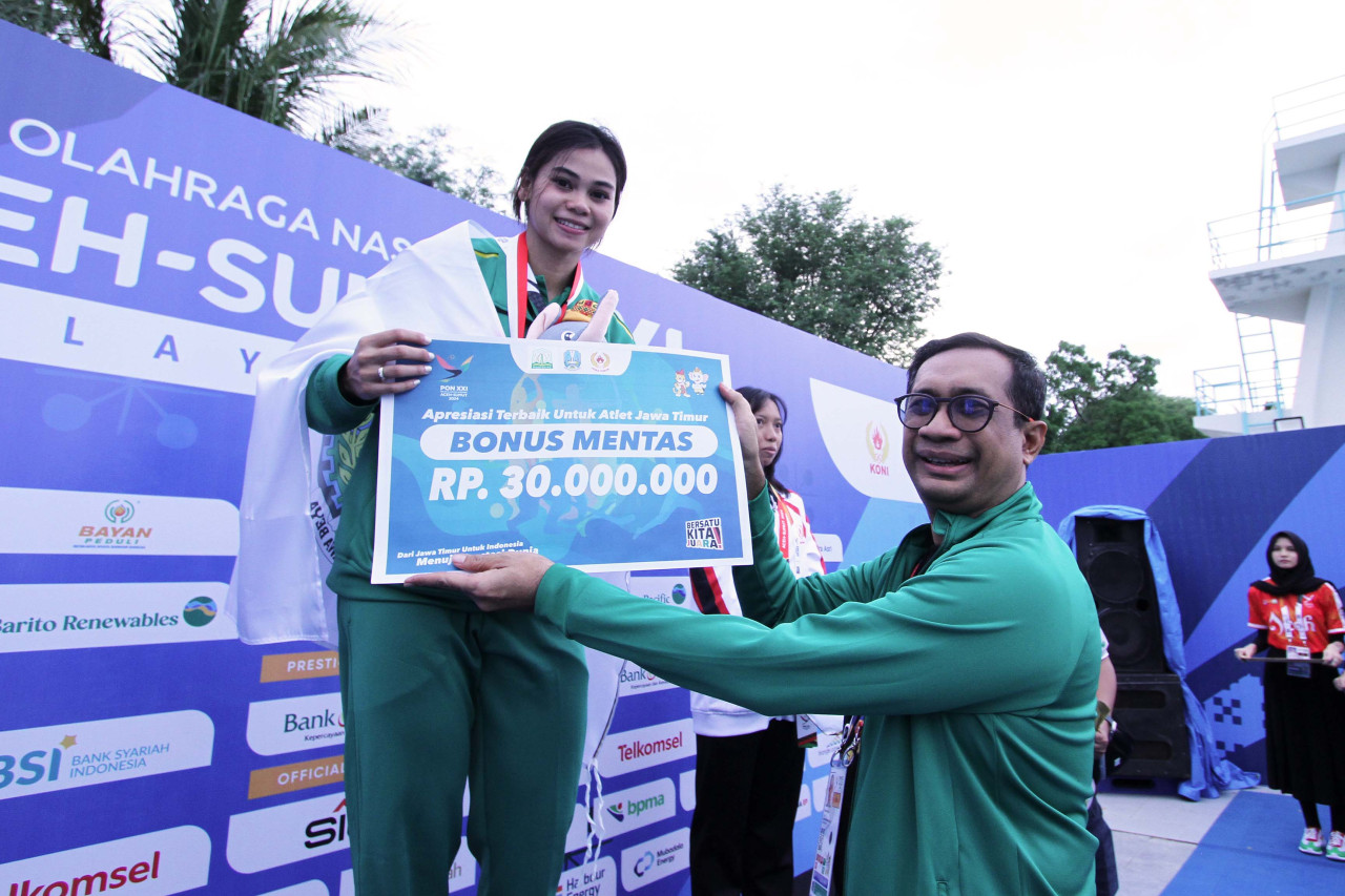 Janis Rosalita Suprianto saat menerima Bonus Mentas dari KONI Jatim seusai upacara penghormatan pemenang selam kolam nomor 100 meter surface putri PON XXI Aceh-Sumut 2024. (Foto: Sahlul Fahmi/jatimnow.com)