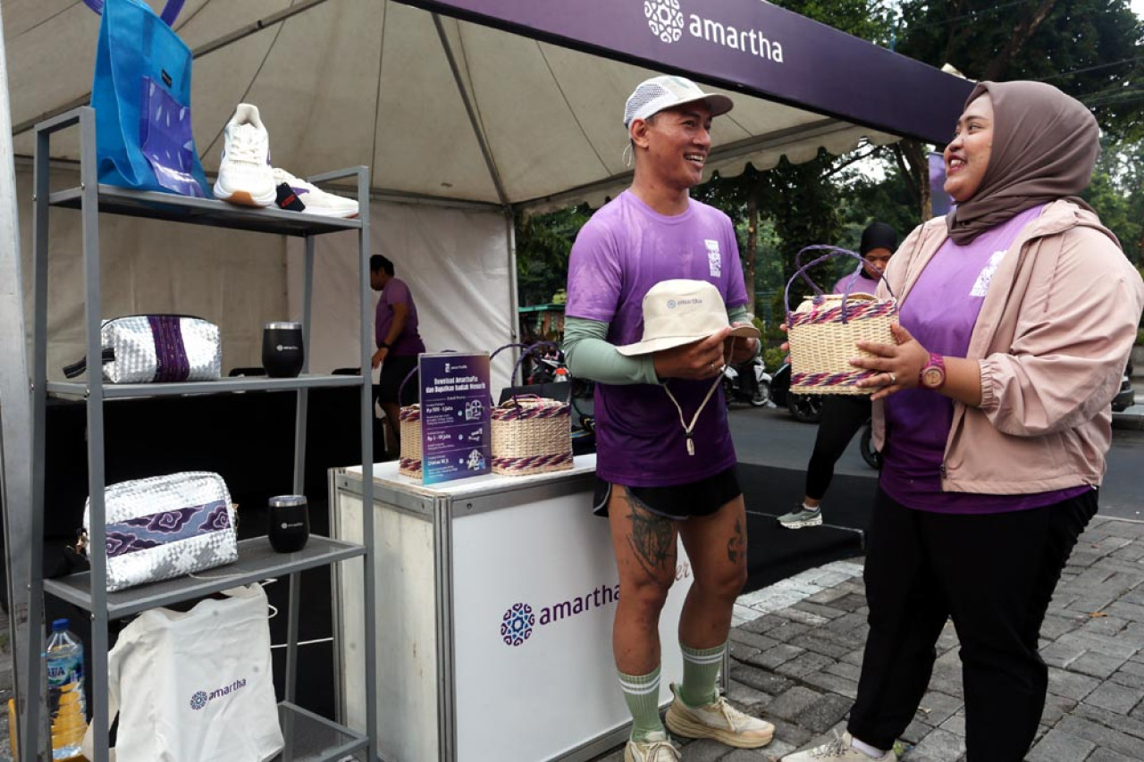 Head of Marketing Amartha, Fenny Febri Krisdayanti (kanan), berbincang dengan Kelvin, salah satu peserta Sunday Morning Run, di lapak UMKM binaan Amartha, di Coffee Toffee Taman Apsari Surabaya. Foto: Ali Masduki/JatimNow.com