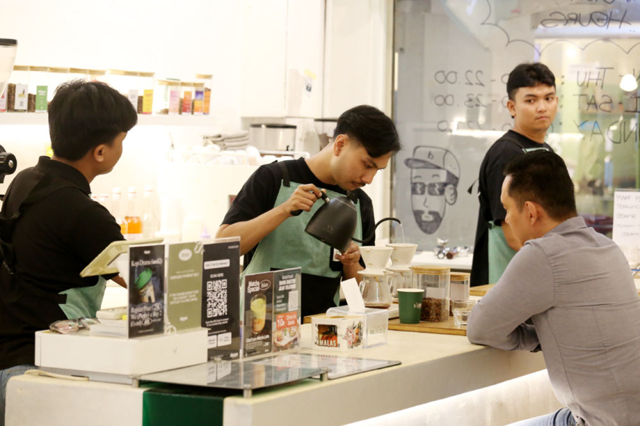 Barista menyajikan kopi pesanan pelanggan di Cafe Drama Roastery, Jl. Tunjungan Surabaya, Jawa Timur, Senin (04/8/2025). Cafe berjejaring ini merupakan salah satu pengguna kopi Arabika dari Lereng Gunung Arjuna. Foto: Ali Masduki/JatimNow.com