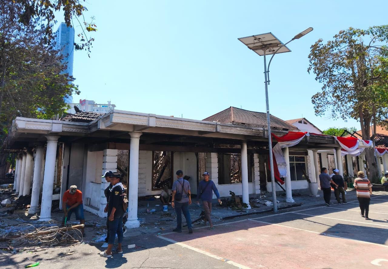 Petugas membersihkan puing sisa kebakaran di sisi barat Gedung Negara Grahadi. (Foto: Naufal for JatimNow.com)