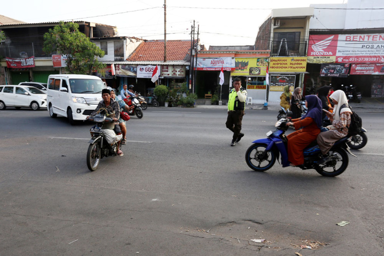 Petugas keamanan membantu menyeberangkan pengunjung Pasar Induk Surabaya Sidotopo 