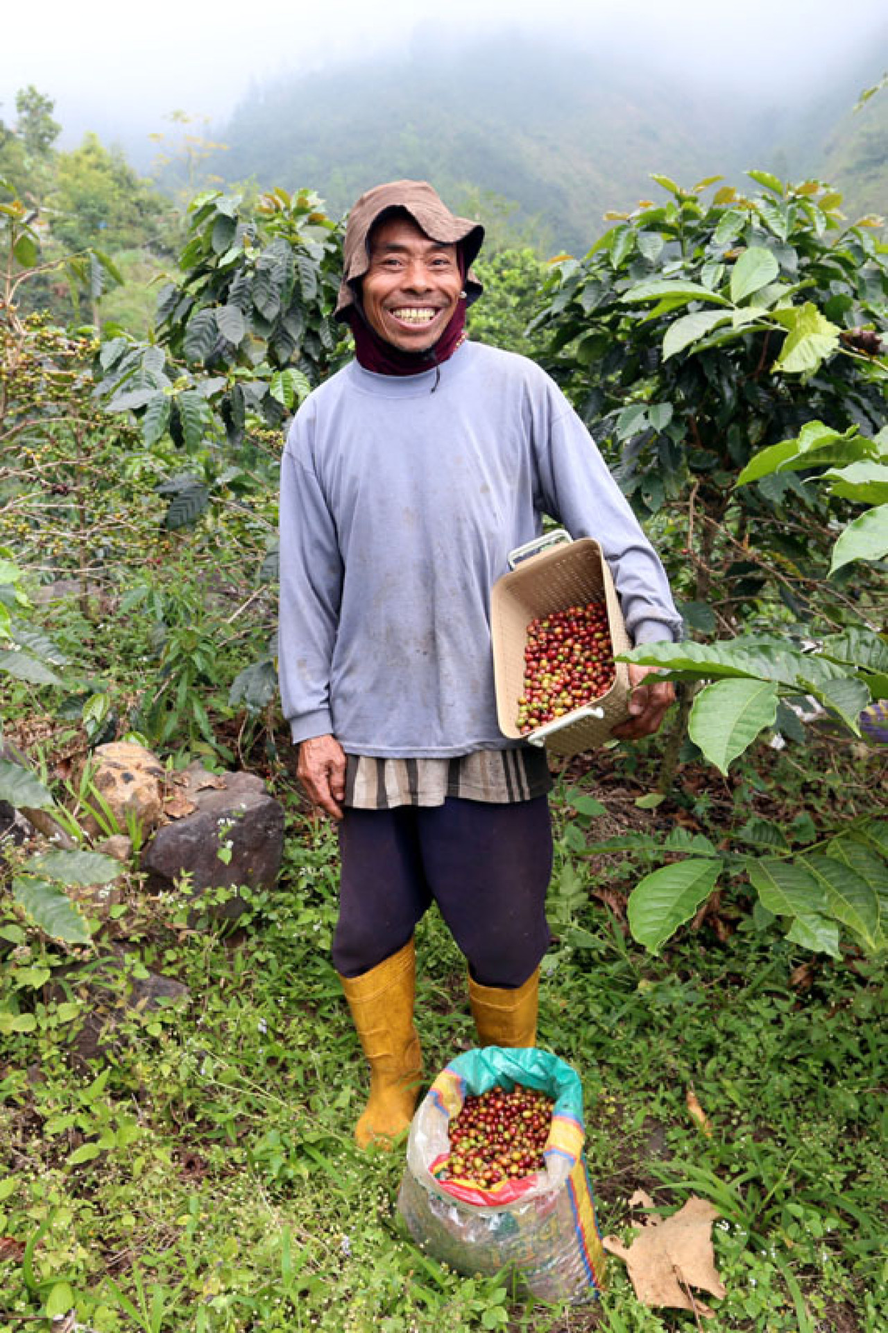 Asmari, buruh petik kopi berpose disela-sela memetik kopi Arabika di Lereng Gunung Arjuna, Dusun Tegal Kidul, Desa Jatiarjo, Kecamatan Prigen, Kabupaten Pasuruan, Jawa Timur, Senin (04/8/2025). Foto: Ali Masduki/JatimNow.com