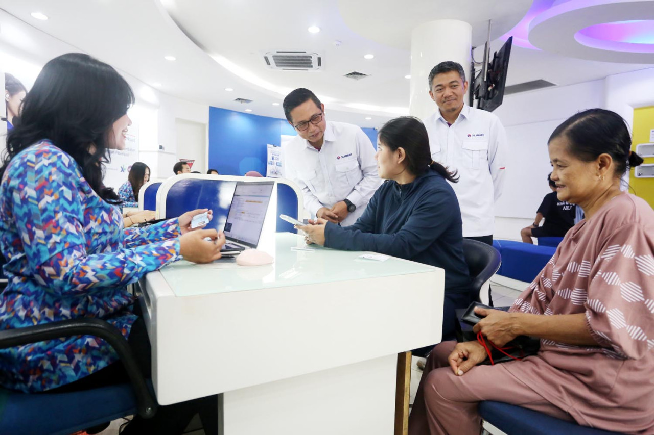 Group Head East Region XLSMART Dodik Ariyanto, bersama Head Direct Channel Region East XLSMART Noval P Wedhasmara, berbincang dengan pelanggan di XL Center Pemuda Surabaya, Kamis (04/9/2025). (Foto: Ali Masduki/JatimNow.com)