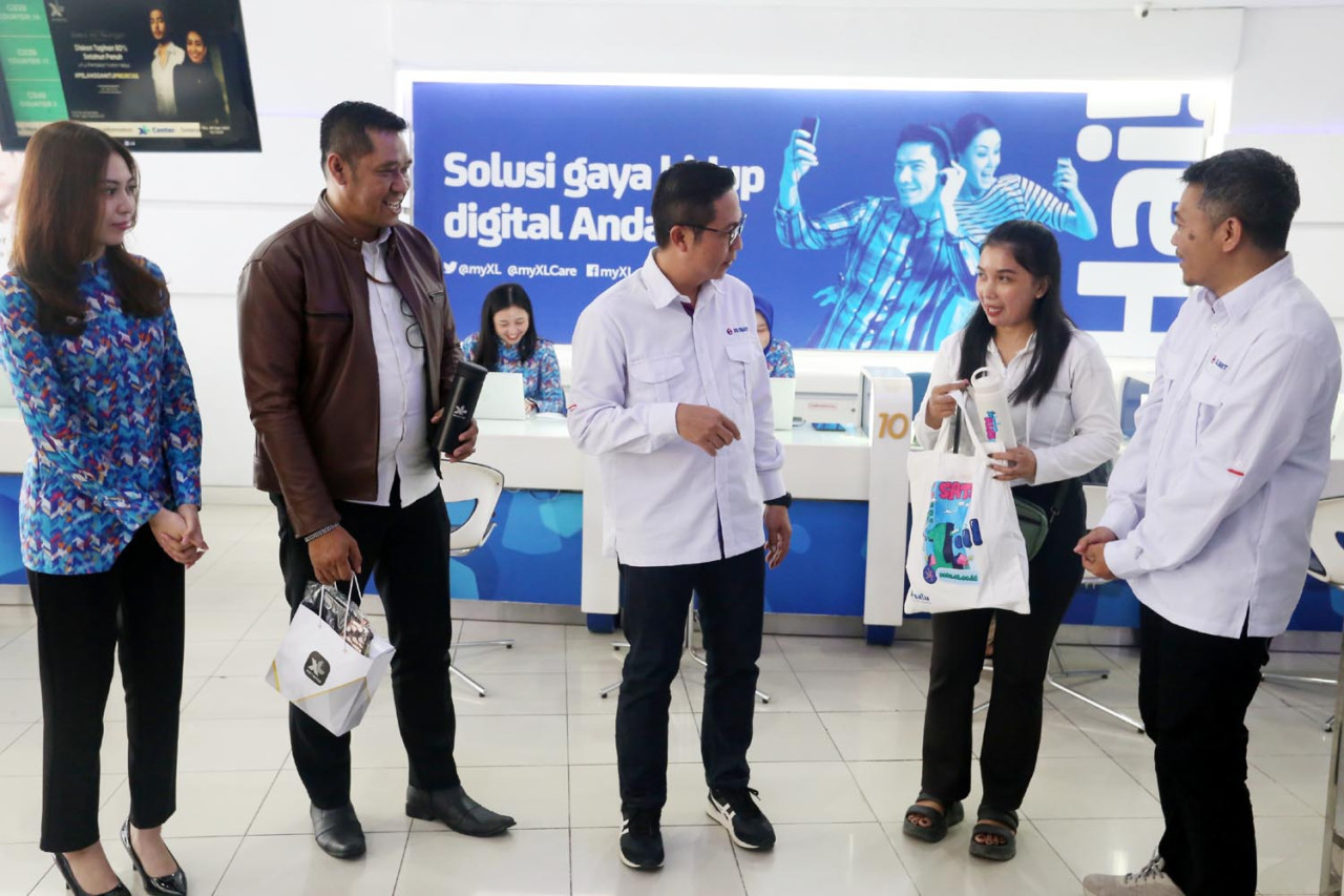 Group Head East Region XLSMART Dodik Ariyanto, bersama Head Direct Channel Region East XLSMART Noval P Wedhasmara, berbagi merchandise kepada pelanggan di XL Center Pemuda Surabaya, Kamis (04/9/2025). (Foto: Ali Masduki/JatimNow.com)
