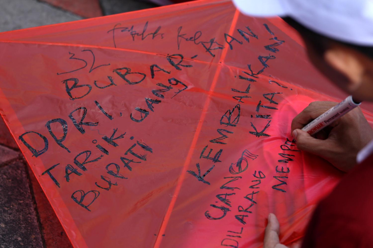 Mahasiswa baru UM Surabaya menulis aspirasi di layangan miliknya ketika mengikuti pembukaan Mastama, Ordik, Expo UKM (MOX) 2025) pada Rabu (17/9/25). (Foto: Ali Masduki/JatimNow.com)