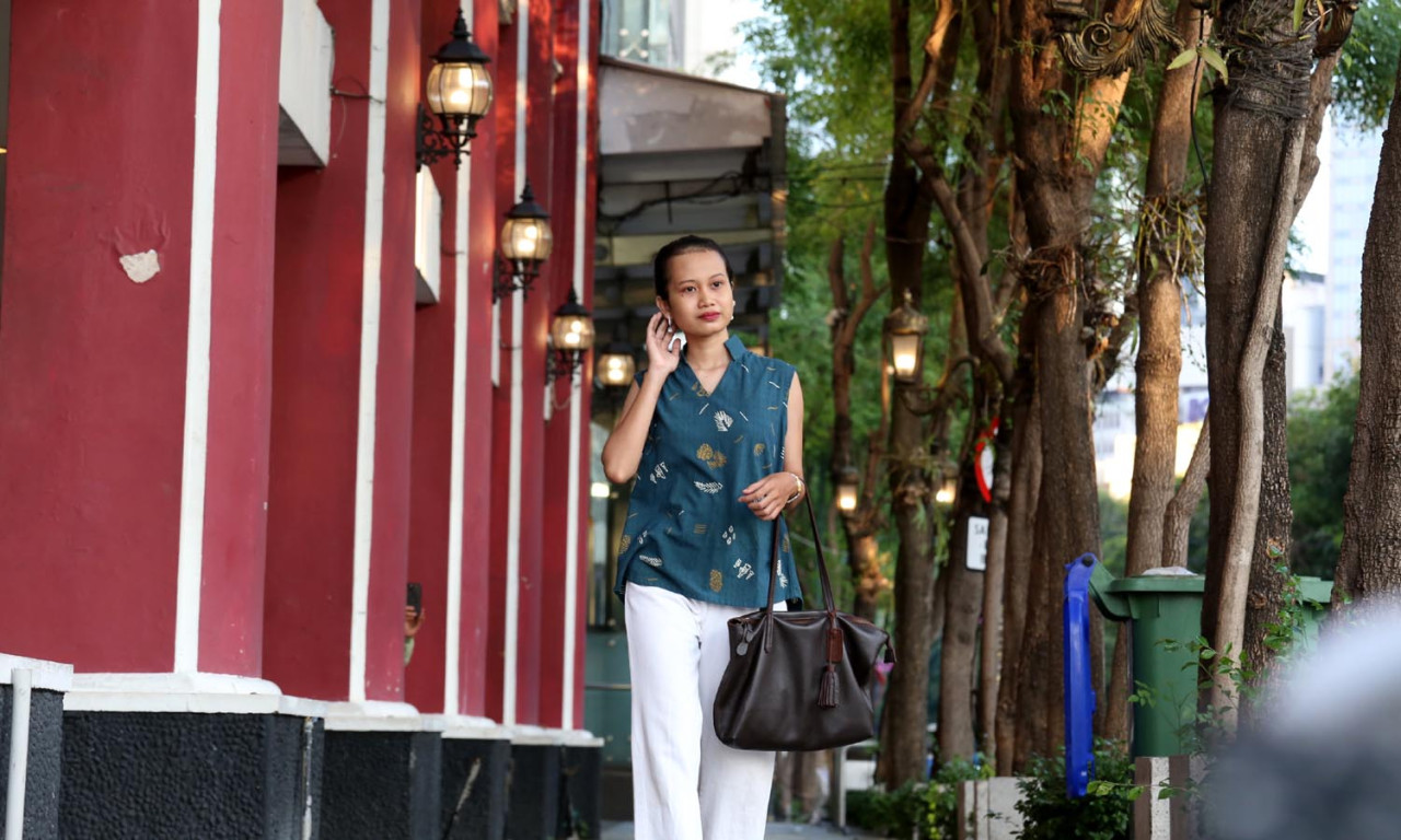 Model berjalan di trotoar mengenakan batik motif teduh batik tulis. Busana ini cocok untuk usia 28-45 tahun. (Foto: Ali Masduki/JatimNow.com)
