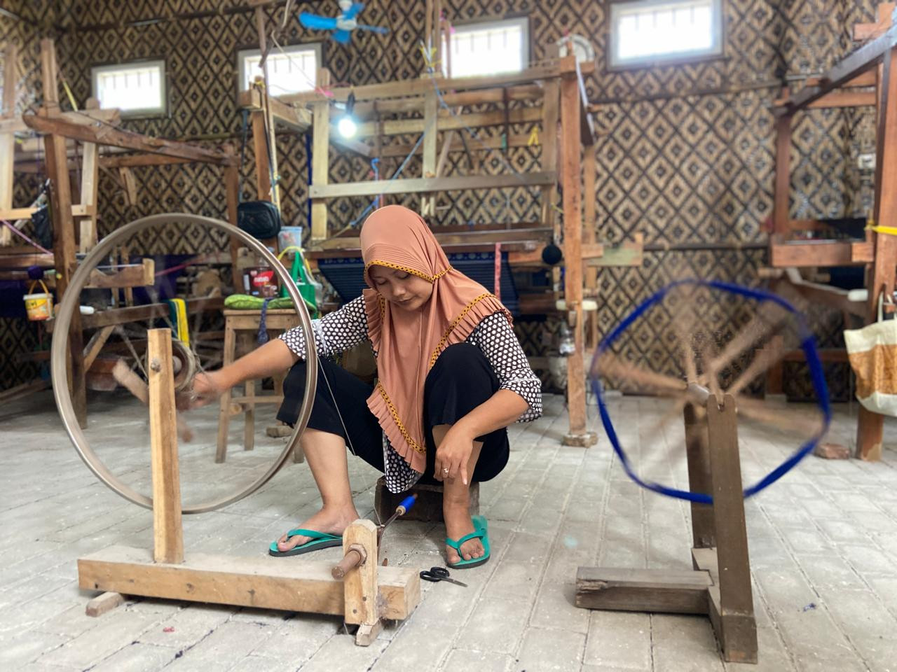 Mira sedang melakukan pemintalan benang di gerai kedua Medali Mas. Dia telah bekerja di sana selama 11 tahun.