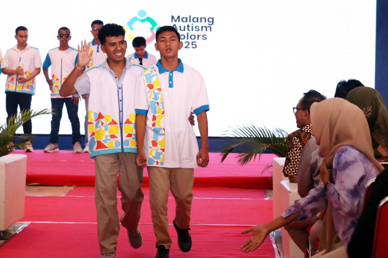 Penyandang Autism Spectrum Disorder (ASD) terlihat percaya diri dan elegan, mengenakan outfit dominasi putih dengan aksen warna cerah biru, cyan, kuning, dan oranye yang menampilkan pola geometris dinamis. (Foto: Ali Masduki/jatimnow.com)