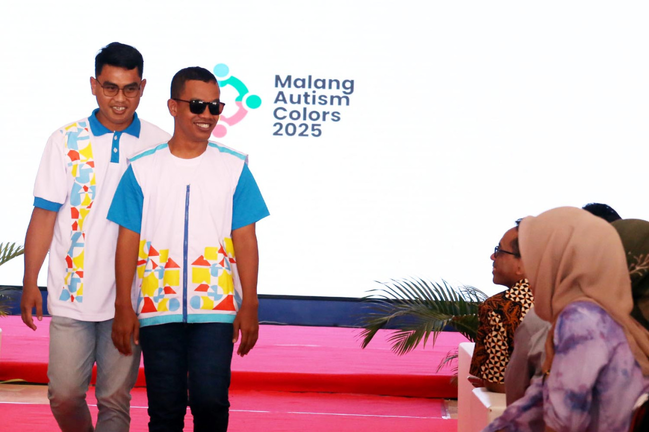 Senyum Penuh Makna. Seorang penyandang Autism Spectrum Disorder (ASD) melangkah dengan percaya diri di panggung fashion show Malang Autism Colors 2025 di MCC, didampingi oleh pendampingnya (Foto: Ali Masduki/jatimnow.com)