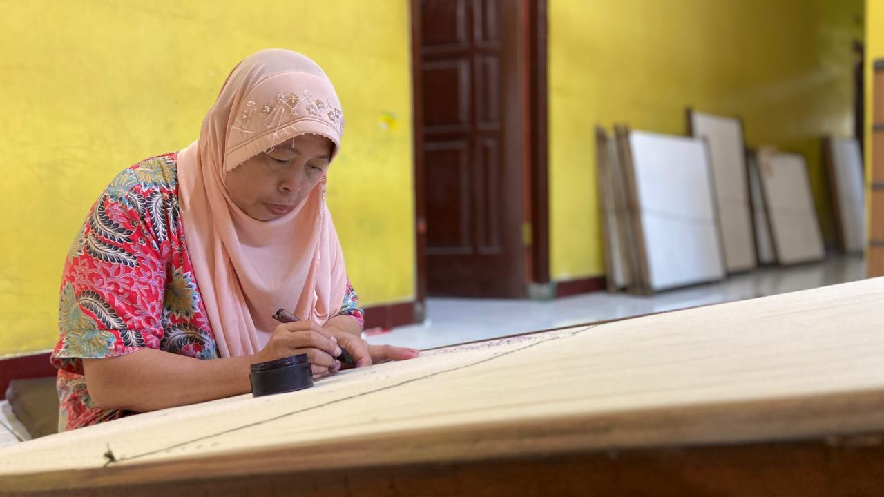 Siti Ruqoyah, perajin kain tenun ikat tertua saat ini, sedang mendesain kain tenun bermotif Tirto Wajik di gerai Medali Mas miliknya. (Foto: Yanuar Dedy/jatimnow.com)