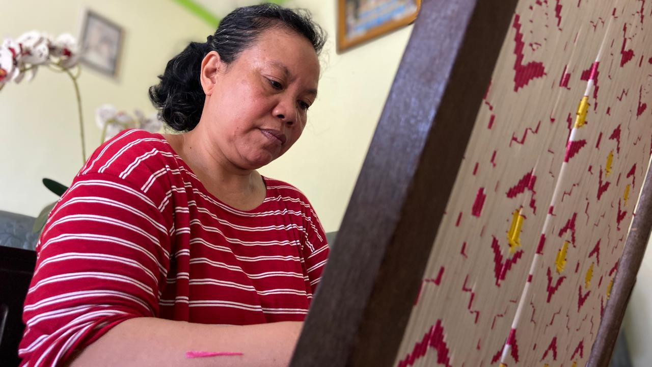 Umaha sedang mengikat benang di rumahnya. Dia bekerja untuk Medali Mas sejak puluhan tahun. (Foto: Yanuar Dedy/jatimnow.com)