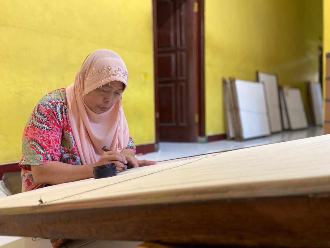 Siti Ruqoyah (56) sedang membuat desain pesanan seragam untuk siswa SD dan SMP di Kota Kediri 2026. Dia merupakan generasi tertua di Kampung Tenun Ikat Bandar Kidul, Kota Kediri, saat ini yang masih aktif. Siti meneruskan suaminya, Munawar, yang memilih istirahat.