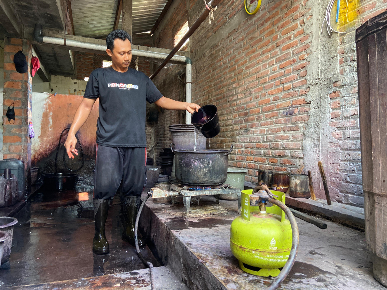 Syaifudin Zuhri (37) sedang menuang air ke dalam panci tanggung di atas kompor gas satu tungku berbahan bakar LPG 3 kilogram untuk direbus. Air panas ini digunakan untuk mencampur zat pewarna benang. Panas stabil dari pembakaran yang sempurna menjadikan warna lebih kuat dan menyala.