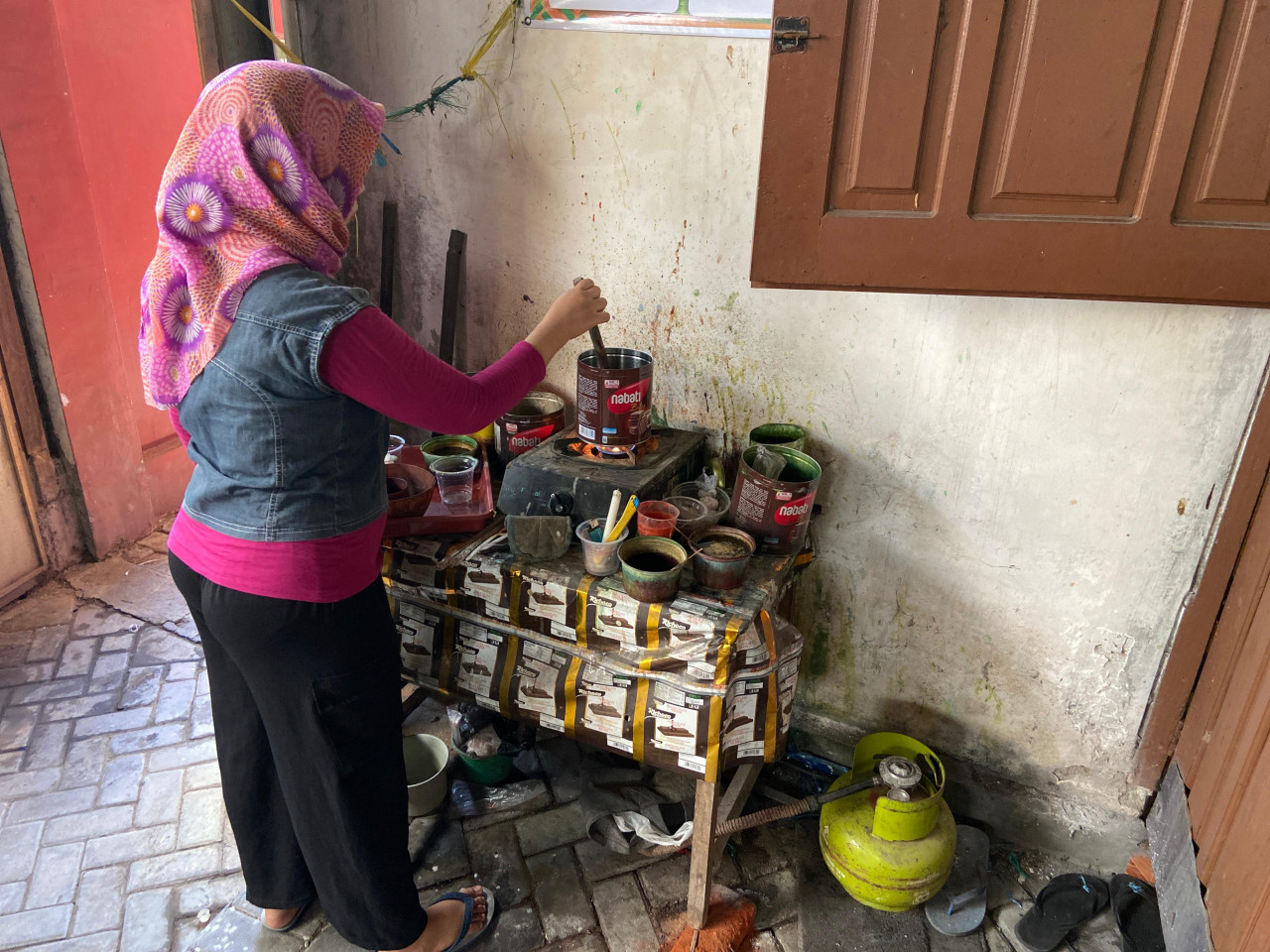Nuraini (35) sedang merebus zat pewarna yang akan digunakan untuk proses colet atau pemberian warna kombinasi. Ini juga memerlukan pengapian sempurna agar warna kombinasi berpadu sempurna dengan warna utama. Dulu prosesnya juga dilakukan dengan kayu bakar yang asapnya bisa memenuhi ruangan.