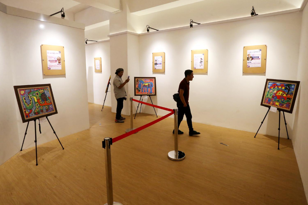Pengunjung melihat lukisan karya anak autisme di di Malang Creative Center atau MCC. (Foto: Ali Masduki/jatimnow.com)