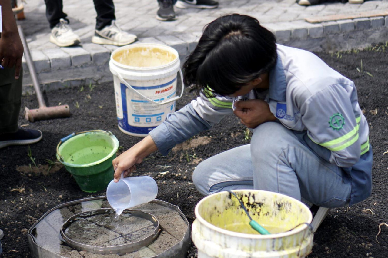 Salah satu mahasiswa ITS saat melakukan pengujian infiltrasi pada inovasi paving porous dari fly ash di Desa Sumberejo, Probolinggo. (Foto: Humas ITS for JatimNow.com)