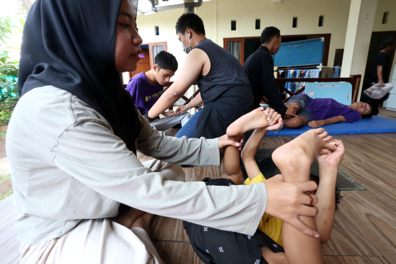 Dengan penuh kesabaran, seorang terapis membantu anak autisme menjalani latihan motorik di Malang Autism Center. Sesi ini melatih keseimbangan dan koordinasi tubuh agar anak lebih sadar akan gerak dan kontrol dirinya. Di ruang sederhana ini, setiap gerakan menjadi langkah kecil menuju kemandirian dan kepercayaan diri bagi anak-anak istimewa. (Foto: Ali Masduki/jatimnow.com)