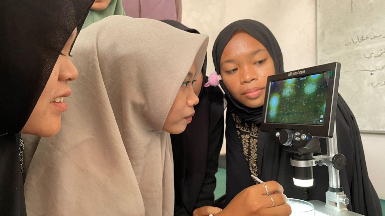 Santriwati PP Nurussalam Bondowoso mengamati dengan seksama tampilan sampel air hujan melalui layar mikroskop digital, Selasa (18/11/2025). (Foto: Prigi Arisandi for JatimNow.com)