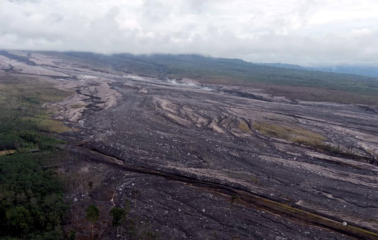 Foto udara ini menampakkan aliran masif material vulkanik berupa abu, pasir, dan bebatuan yang menuruni lereng Gunung Semeru. Area ini, khususnya di sektor tenggara Besuk Kobokan, merupakan zona terlarang (radius 20 km) yang diimbau PVMBG untuk tidak dimasuki oleh warga dan relawan. Tim SAR dan petugas terkait terus memantau pergerakan material ini demi keselamatan operasi evakuasi di Lumajang. (Foto/BPBD)