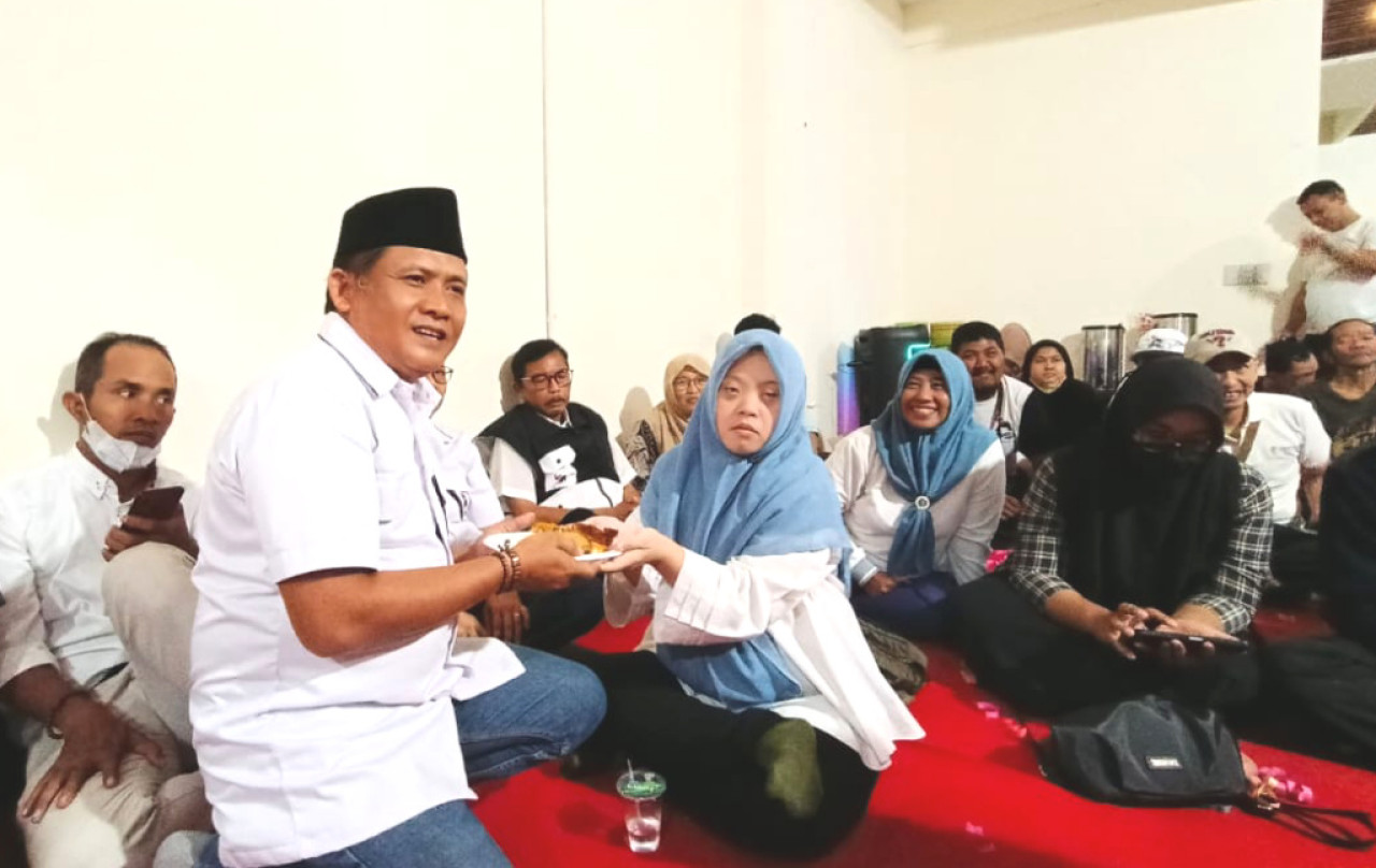 Ketua DPD PSI Surabaya, Shobikin, menyerahkan potongan tumpeng kepada kader sebagai simbol HUT PSI. (Foto: Humas PSI Surabaya for JatimNow.com)