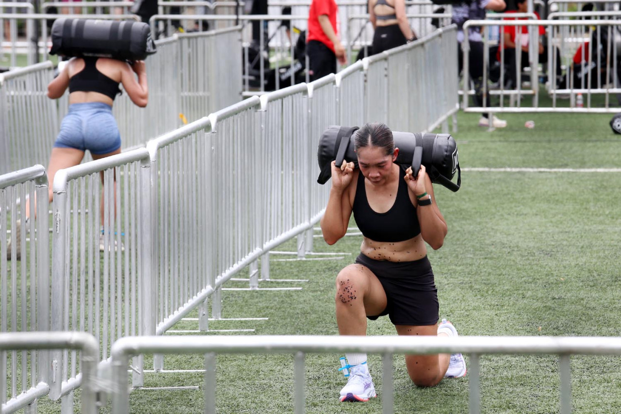 Peserta menyelesaikan tantangan sandbag lunges ketika mengikuti Hybrid Strike 2.0, di Royal Clubhouse & Sports Hub Surabaya, Sabtu (01/11/2025). (Foto: Ali Masduki/jatimnow.com)