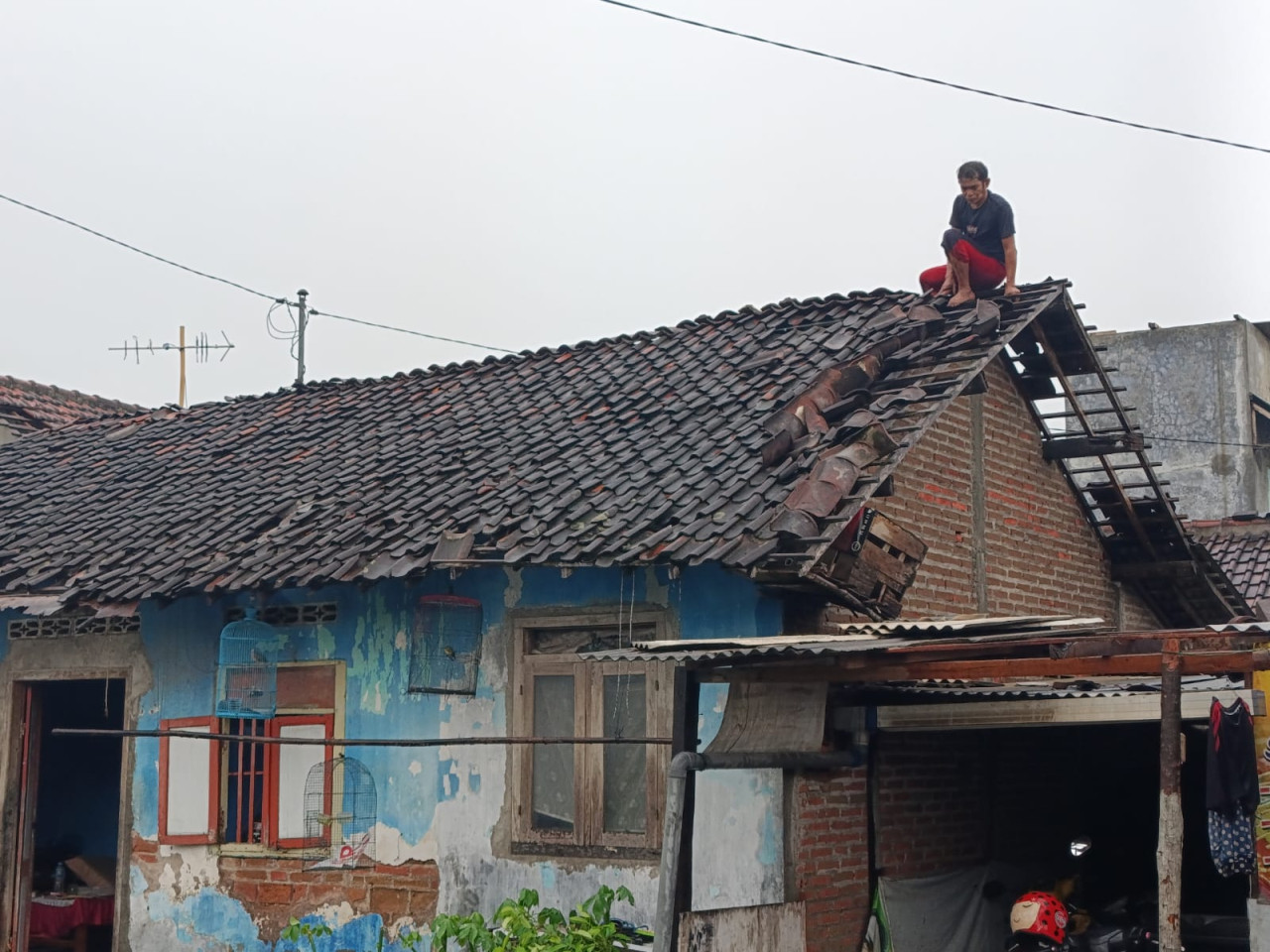 Foto: Warga di Tulungagung perbaiki atap rumah yang rusak terkena angin kencang. (Bramanta/jatimnow.com)