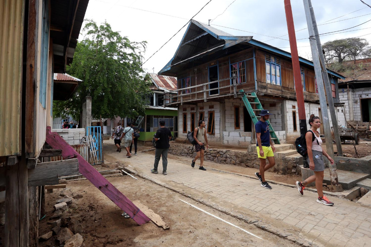 Jalur wisata Pulau Komodo melintas rumah-rumah panggung kayu yang sederhana dan gang sempit yang berkelok. Meskipun hidup dengan predator, semuanya berjalan dengan tenang, tanpa pagar pembatas yang mencolok antara manusia dan makhluk besar yang turut berada di sekitarnya. (Foto: Ali Masduki/JatimNow.com)
