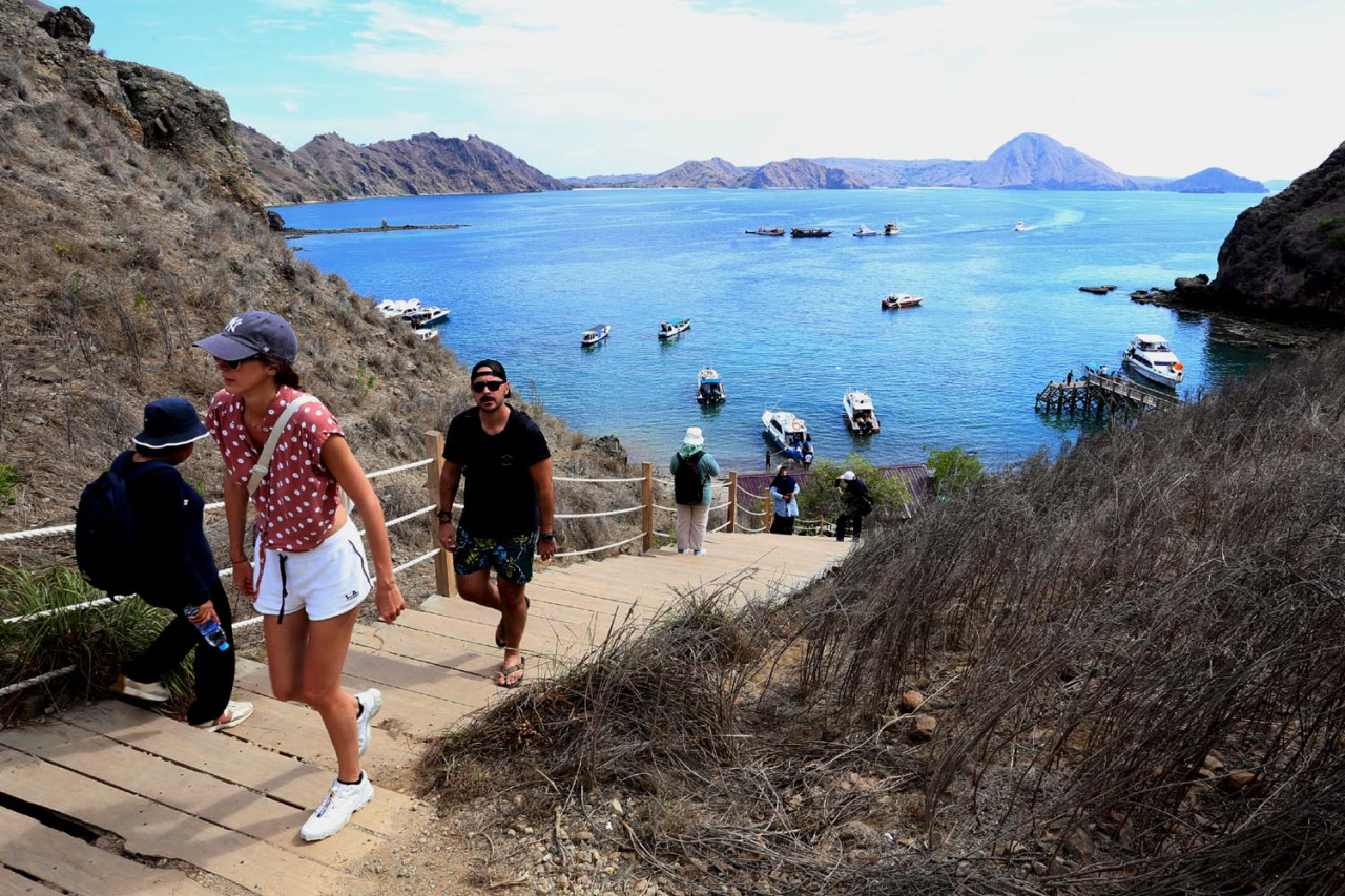 Wisatawan menaiki jalur trekking menuju puncak Pulau Padar, Taman Nasional Komodo, Nusa Tenggara Timur. Jalur ini menjadi akses utama bagi pengunjung untuk menikmati panorama tiga teluk yang menjadi ikon keindahan Pulau Padar. (Foto: Ali Masduki/JatimNow.com)