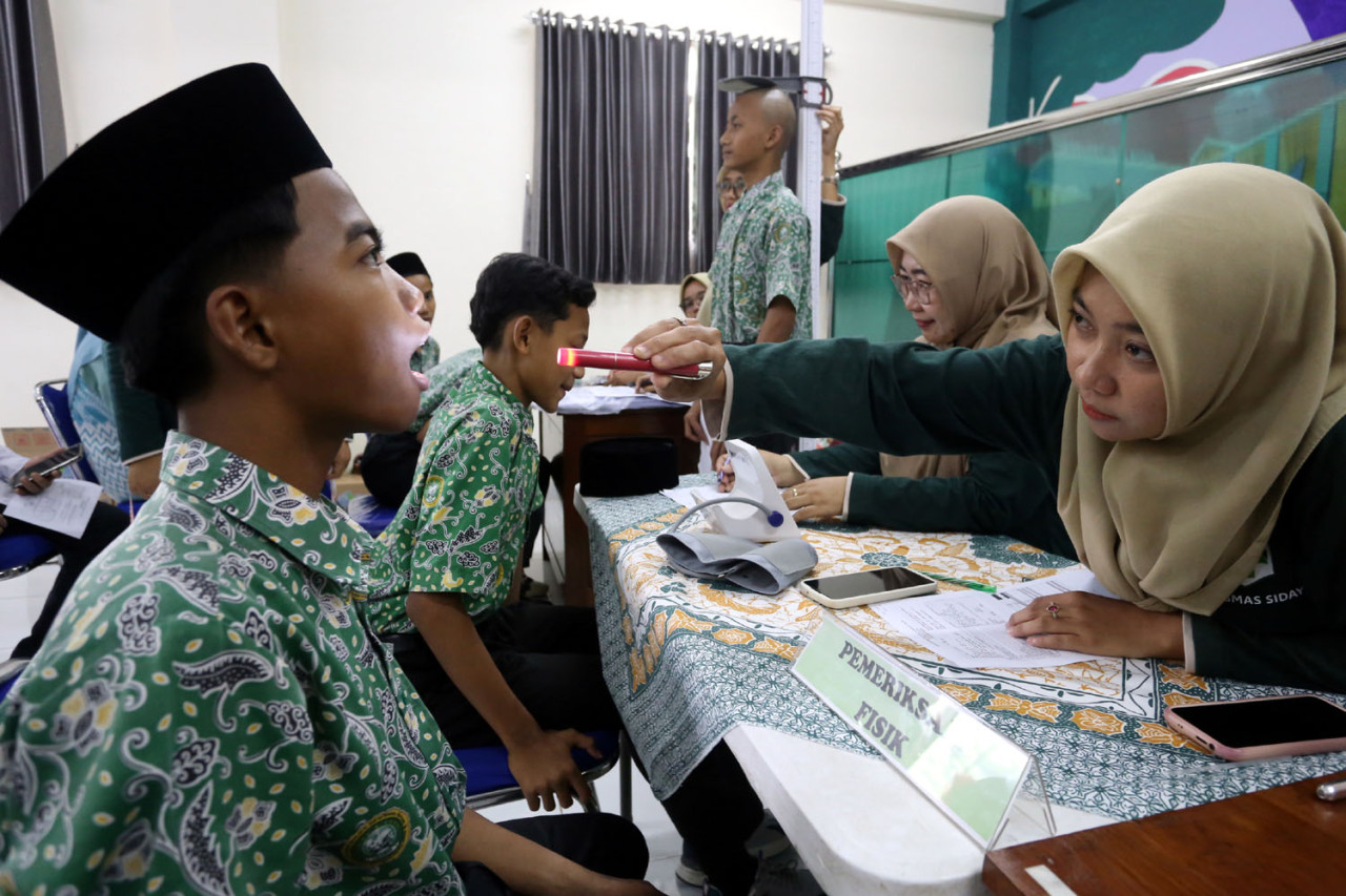 Seorang santri Pondok Pesantren Modern Sunanul Muhtadin, Gresik, menjalani pemeriksaan kesehatan oleh tenaga medis dalam program Cek Kesehatan Gratis (CKG), Kamis (18/12/2025). (Foto: Ali Masduki/jatimnow.com)