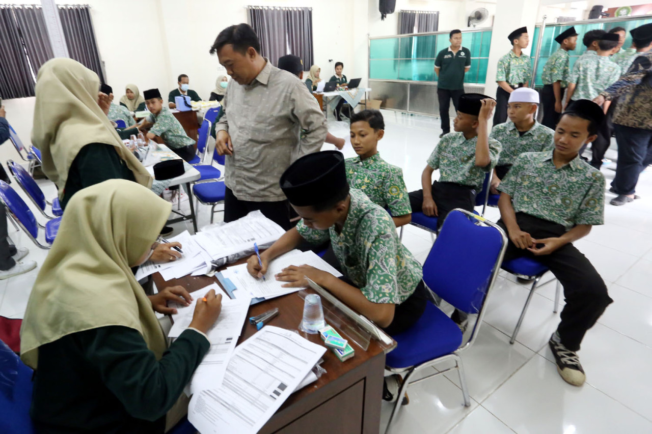 Sejumlah santri Pondok Pesantren Modern Sunanul Muhtadin, Gresik, mengisi data dan menunggu giliran pemeriksaan dalam pelaksanaan Program Cek Kesehatan Gratis (CKG), Kamis (18/12/2025). Kegiatan ini menjadi bagian dari upaya pemerintah memastikan akses layanan kesehatan yang merata bagi santri serta mendukung pencegahan penyakit menular di lingkungan pesantren. (Foto: Ali Masduki/jatimnow.com)