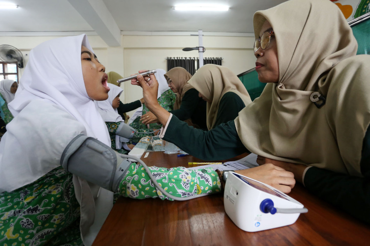 Seorang santriwati Pondok Pesantren Modern Sunanul Muhtadin, Gresik, menjalani pemeriksaan kesehatan oleh tenaga medis dalam Program Cek Kesehatan Gratis (CKG), Kamis (18/12/2025). Pemeriksaan meliputi pengecekan kondisi umum sebagai bagian dari upaya deteksi dini penyakit dan peningkatan layanan kesehatan bagi santri di lingkungan pesantren.(Foto: Ali Masduki/jatimnow.com)