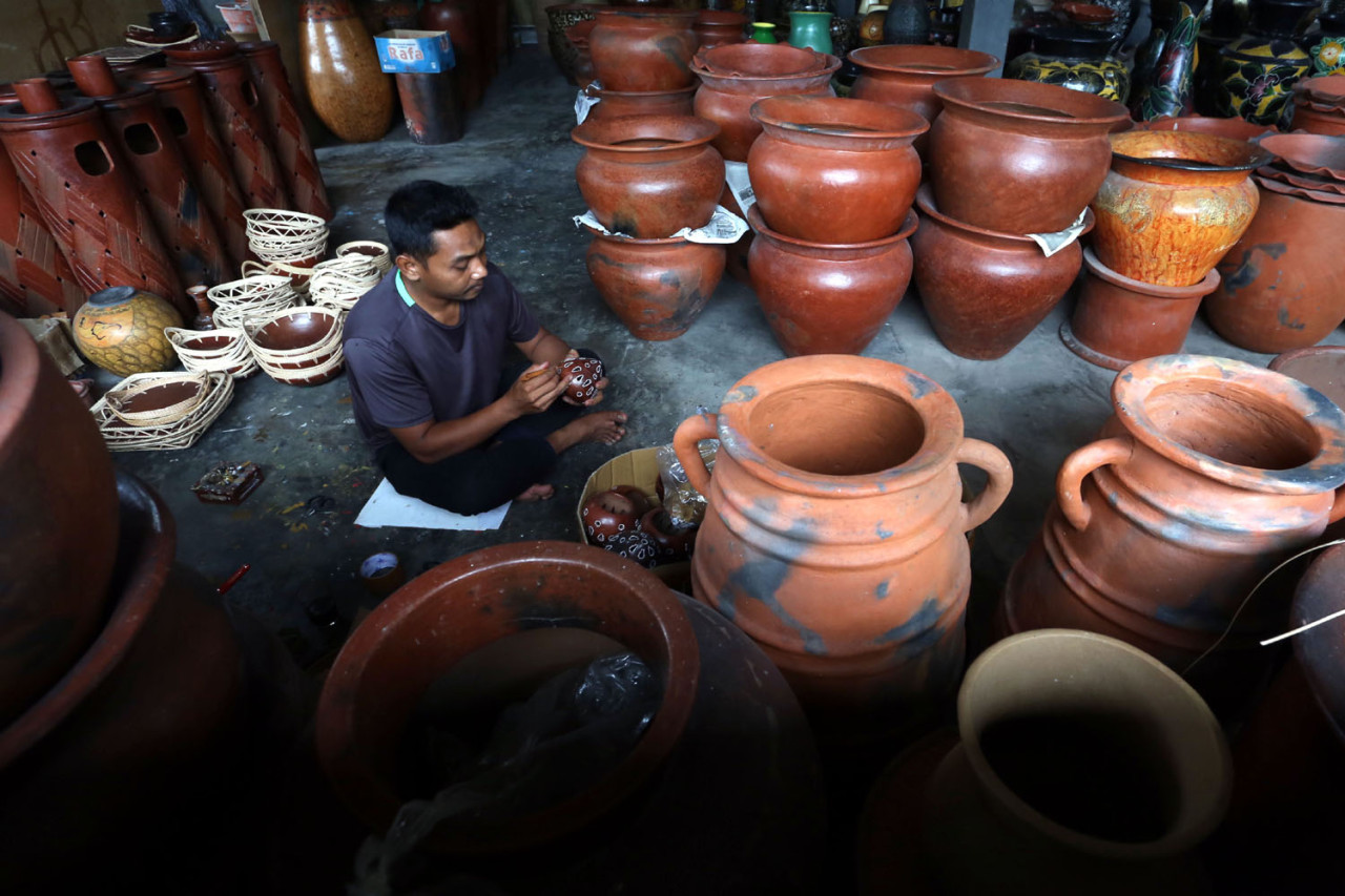 Perajin lokal menyelesaikan ukiran pada gerabah di Banyumulek, Lombok Barat, Sabtu (27/12/2025). Kegiatan ini menjadi galeri hidup di mana tradisi turun-temurun menjelma menjadi komoditas global yang memikat turis mancanegara. (Foto: Ali Masduki/jatimnow.com)